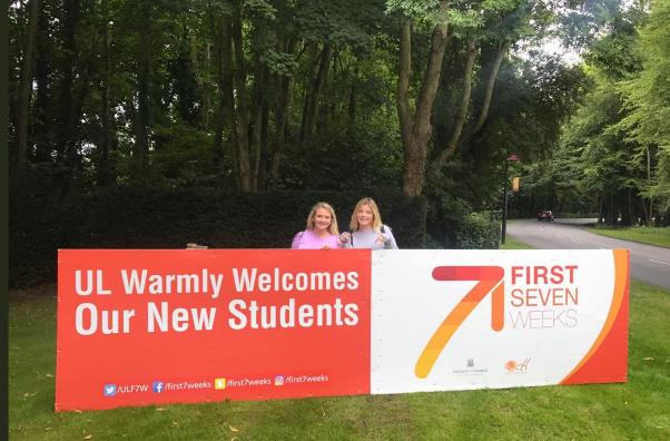 2 girls standing in front of a sign saying 'UL Warmly Welcomes Our New Students'