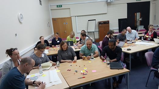 Image of people in groups at a Masterclass writing notes 