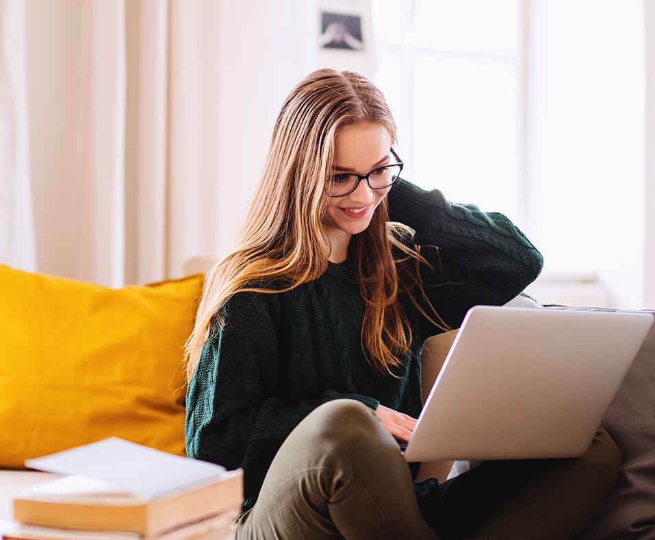 A woman sitting on the couch while looking at her laptop